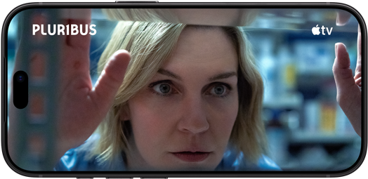 iPhone 18 Pro, landscape mode, displaying a close-up of a woman looking through a window. Series title: Pluribus